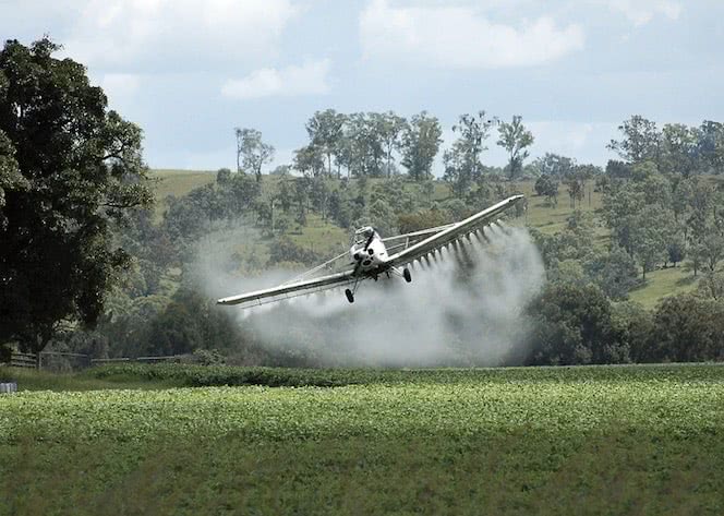 Avião jogando agrotóxico em uma plantação.