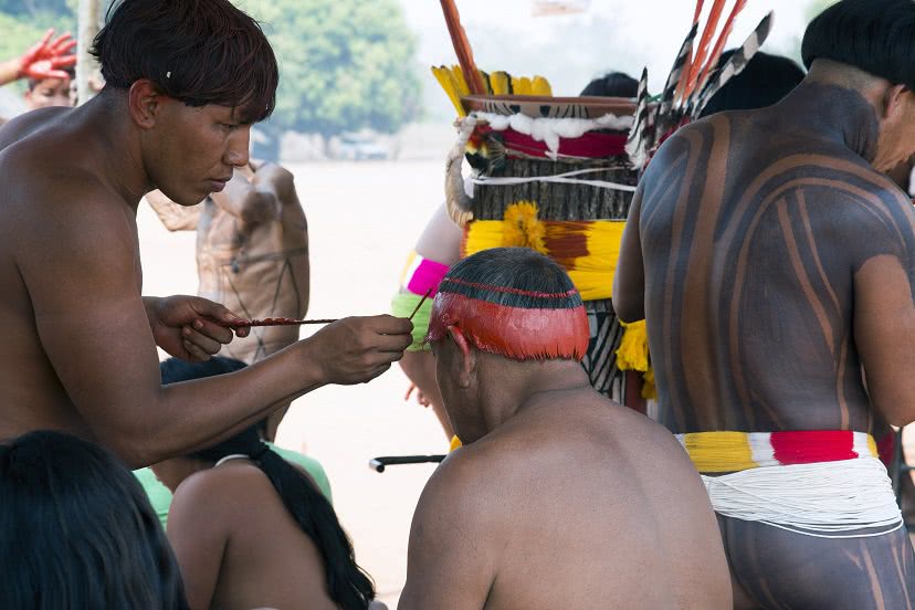 Índios pintando o corpo.