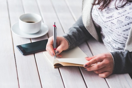 Mulher fazendo anotações em um caderno.