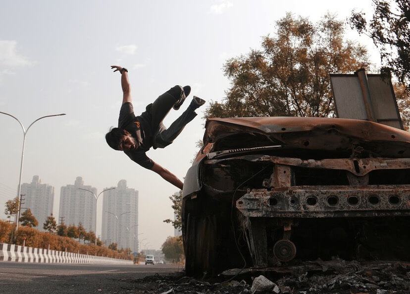 Homem praticando parkour em um carro abandonado.