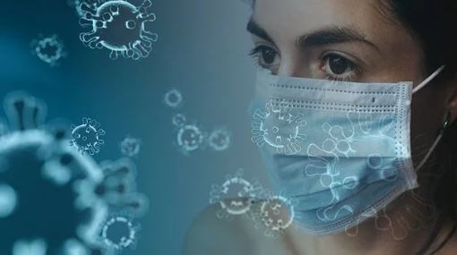 Uma mulher de máscara com imagens de vírus circulando ao fundo.